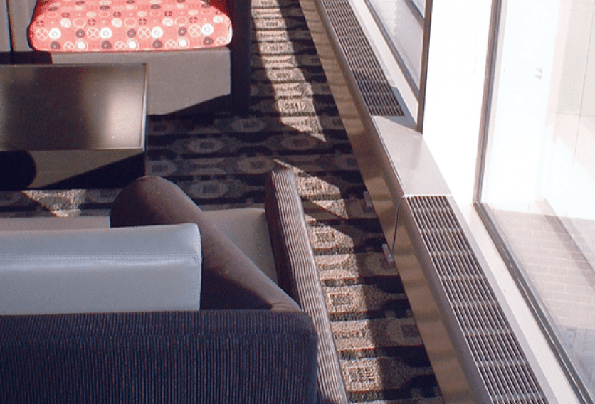 A black and white patterned rug on the floor, surrounded by furniture and a window, with HVAC vents visible