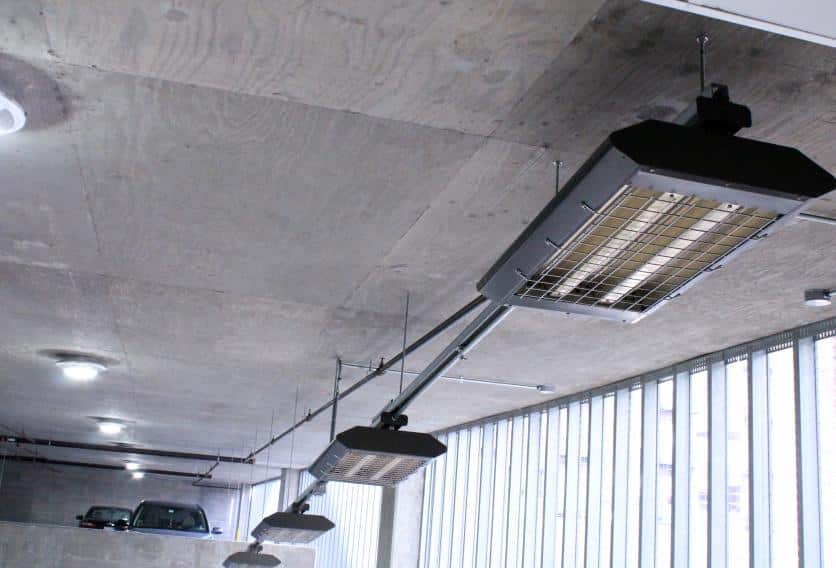 A well-lit parking garage with a ceiling heating unit