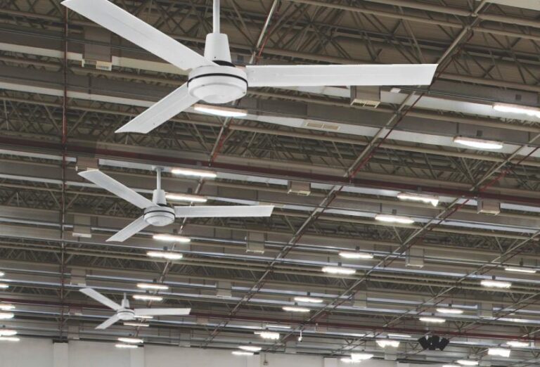 Three large ceiling fans spinning in an industrial warehouse, providing airflow in a spacious, open environment.